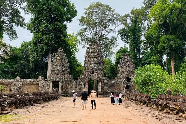 People walking along a stone pathway towards an ancient, towering temple structure.