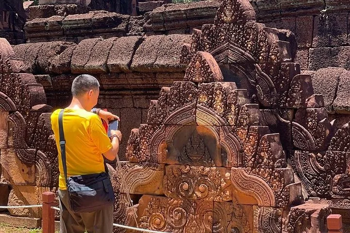 Un turista tomando una foto de un intrincado tallado en piedra en un templo.